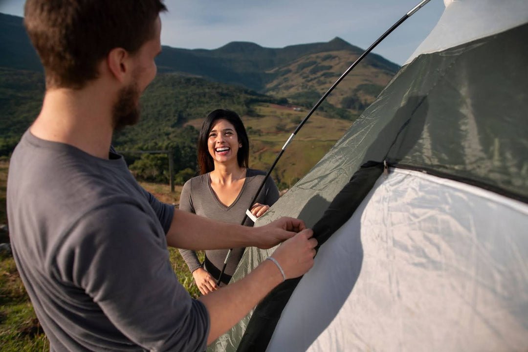 A couple setting up a tent during a camping trip.
